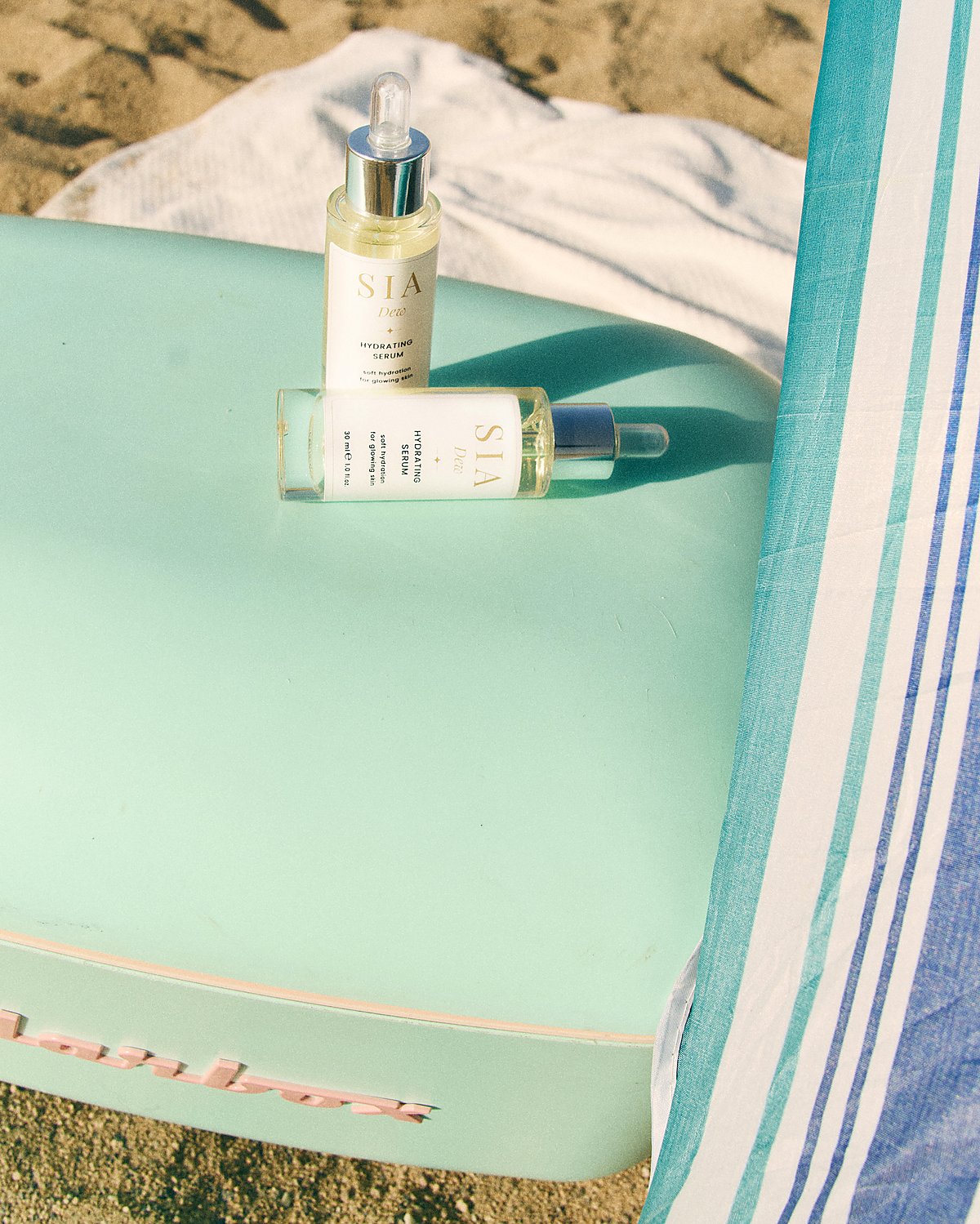 SIA DEW bottles on a surfboard at the beach